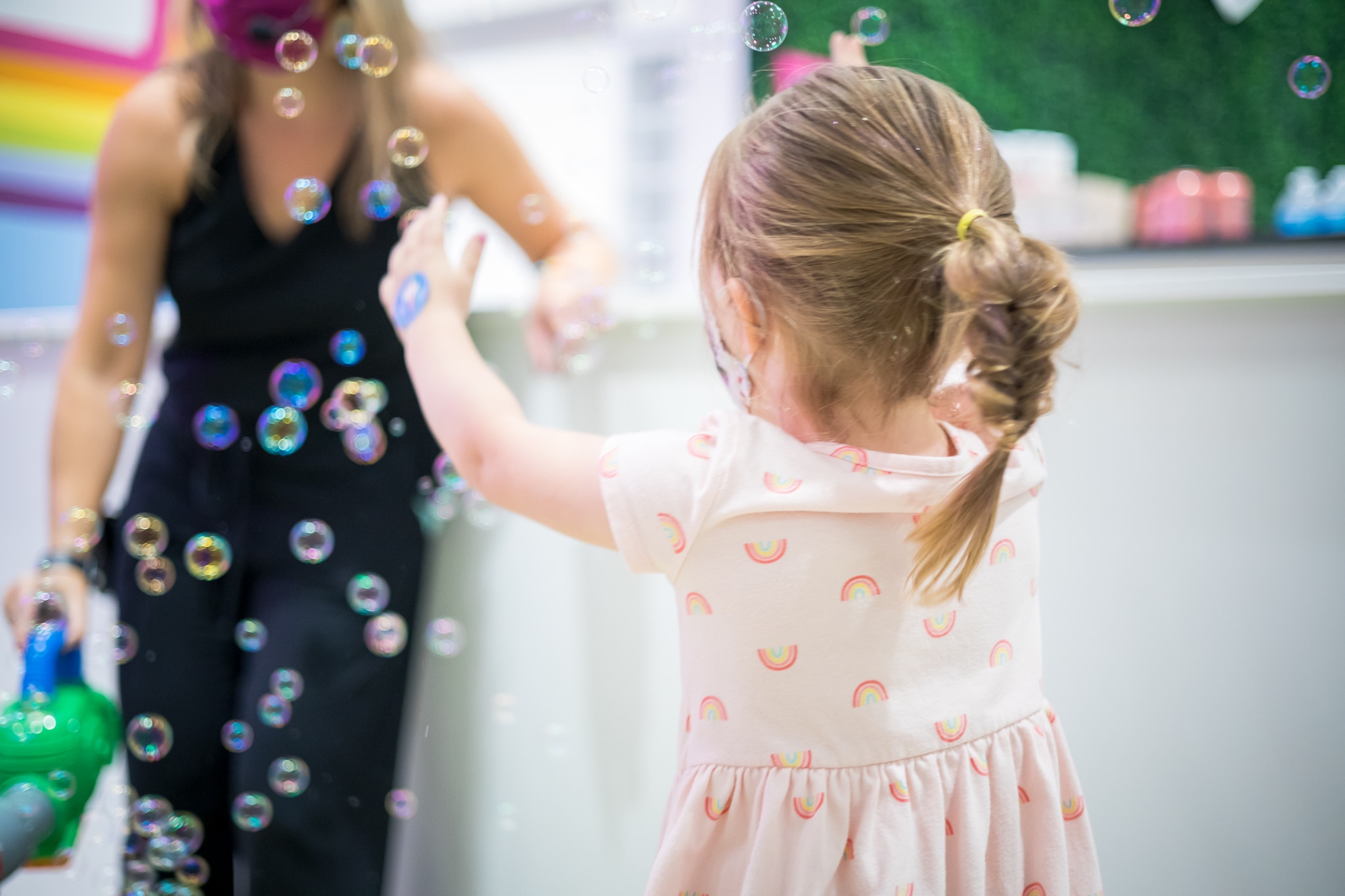 The baby girl, a preschooler, is enjoying the bubbles